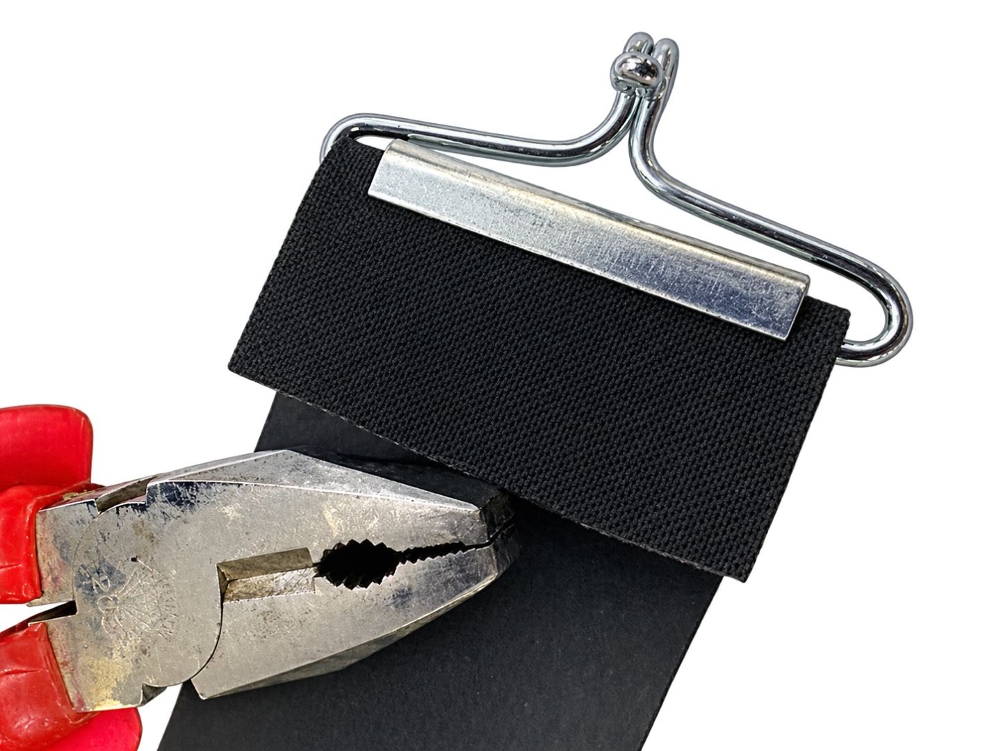 Detail van de singelband, metalen clip en haak met een combinatietang